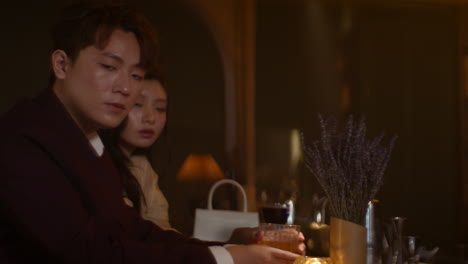 a couple sitting at a bar, tense and ignoring each other during an argument