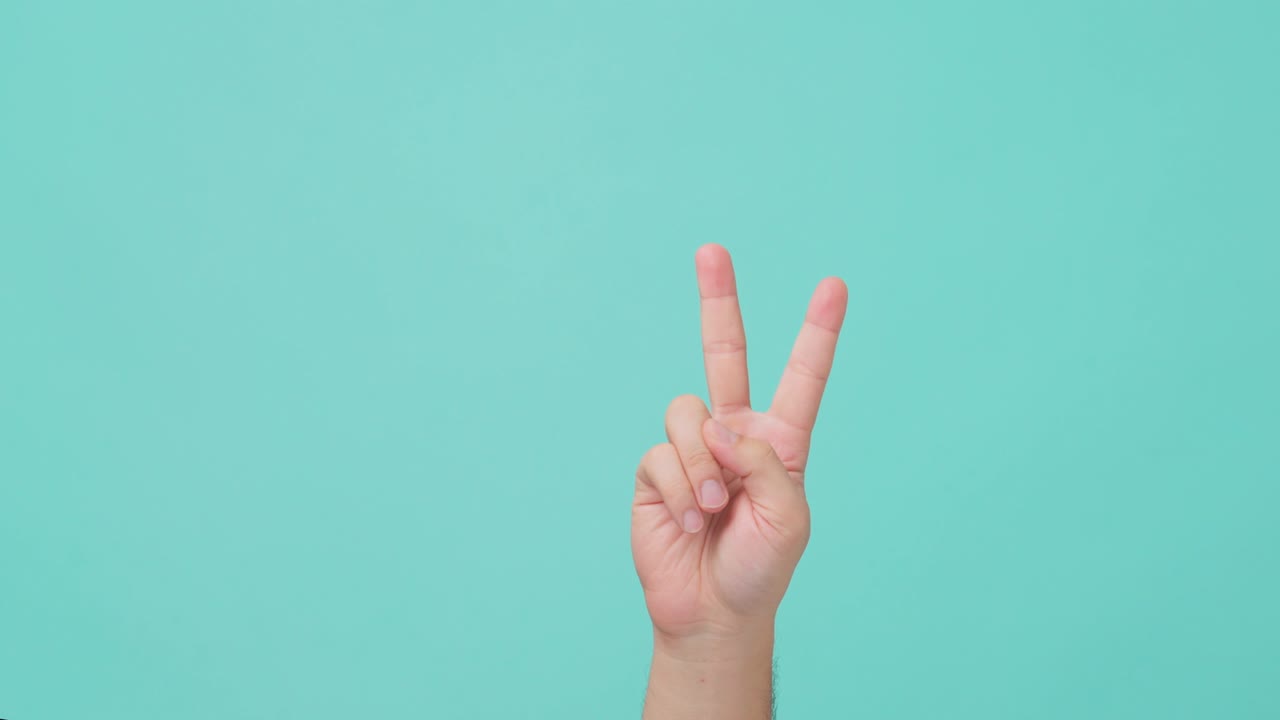 Close up shot of asian human hand raising with two finger, index and middle fingers are raised. the man showing v sign victory gesture in isolate blue screen in background.