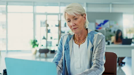 mujer anciana trabajando en una computadora portátil en la oficina