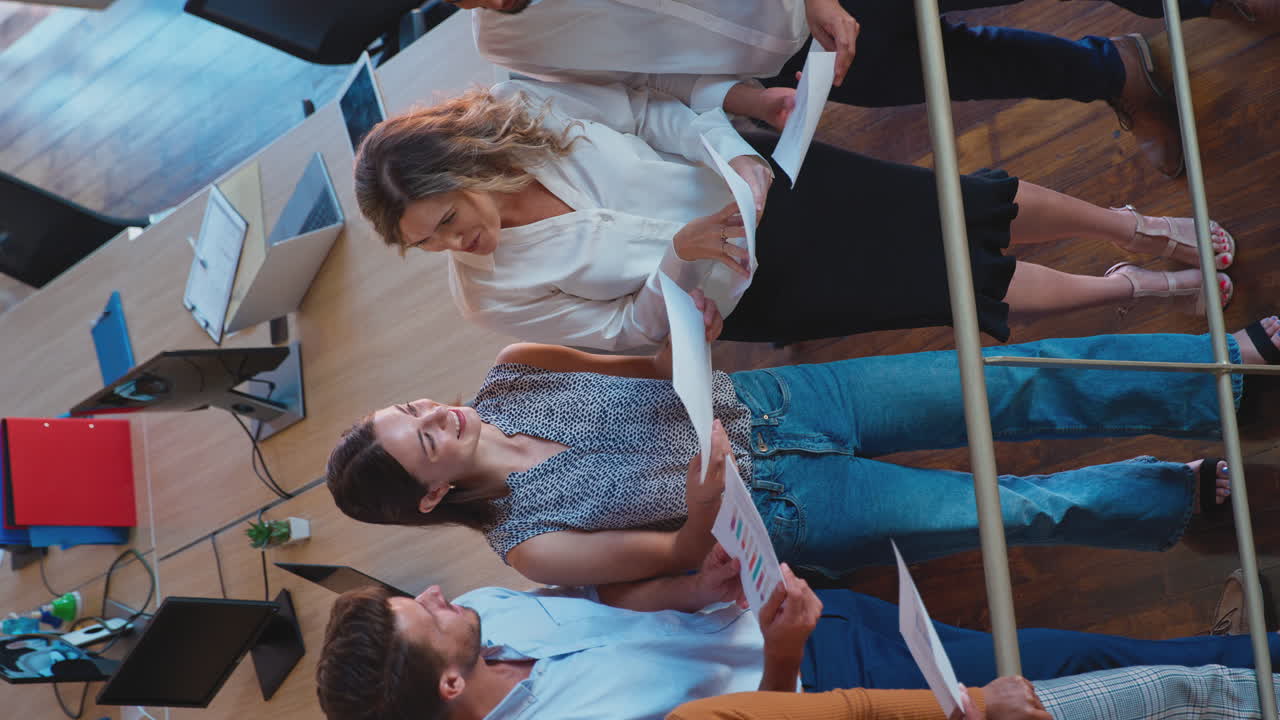 video vertical de una mujer de negocios en una reunión de equipo en una oficina multicultural entregando documentos