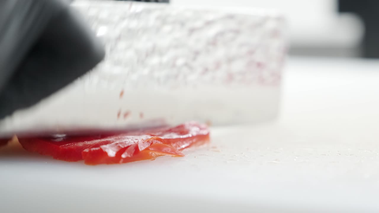 el cocinero corta la pimienta roja con un hermoso cuchillo