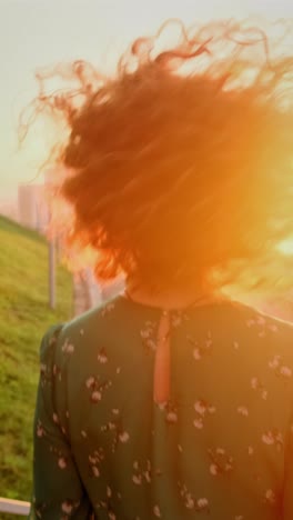 woman with curly red hair in sunrise/sunset view