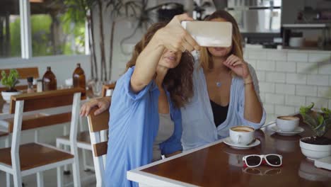 two women taking a selfie in a cafe