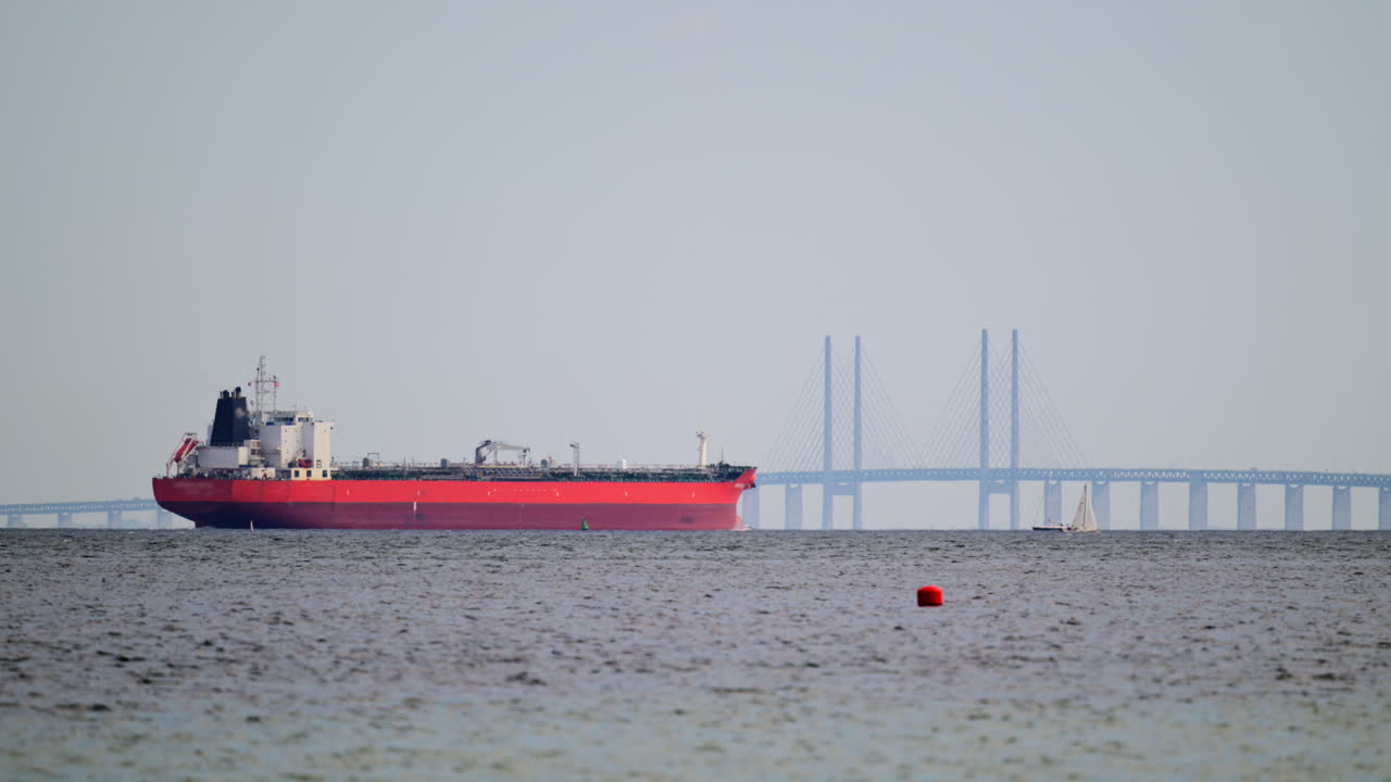 Red tanker sailing along the Oresund Strait with the iconic Oresund Bridge in the background. Copenhagen, Denmark