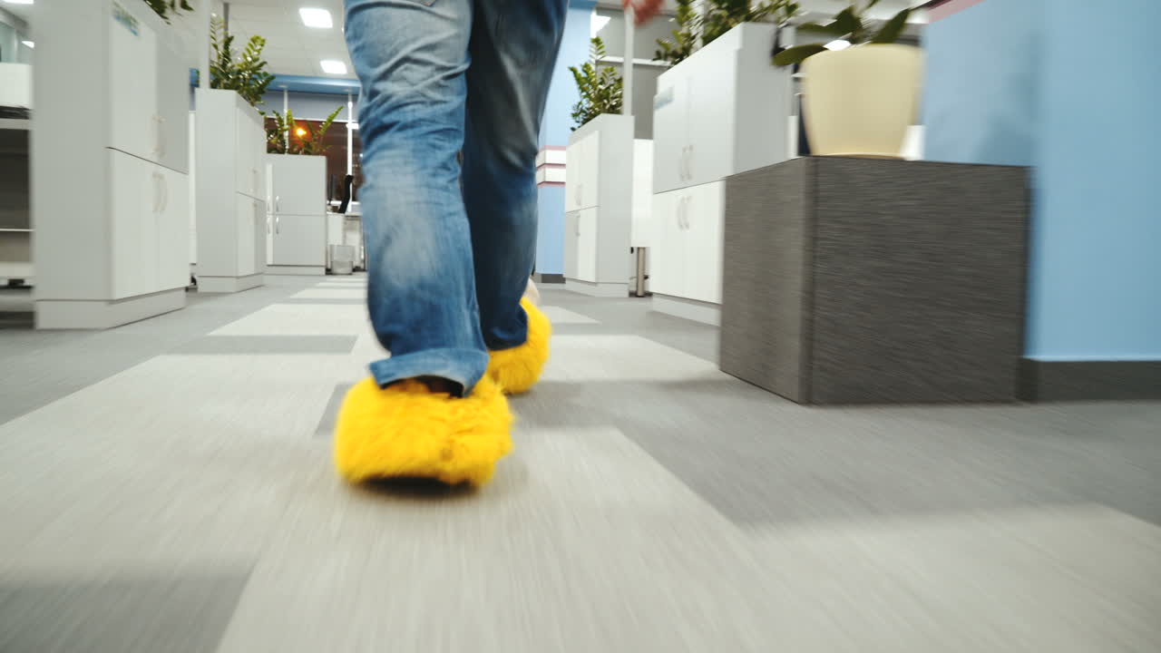 Office worker is running around in funny shoes. Male legs close-up walking around the office.