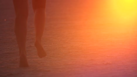 Slow-Motion-shot-of-girls-running-through-sand-kicking-it-up-in-the-air-with-the-glow-of-the-sunset-reflecting-in-the-sand