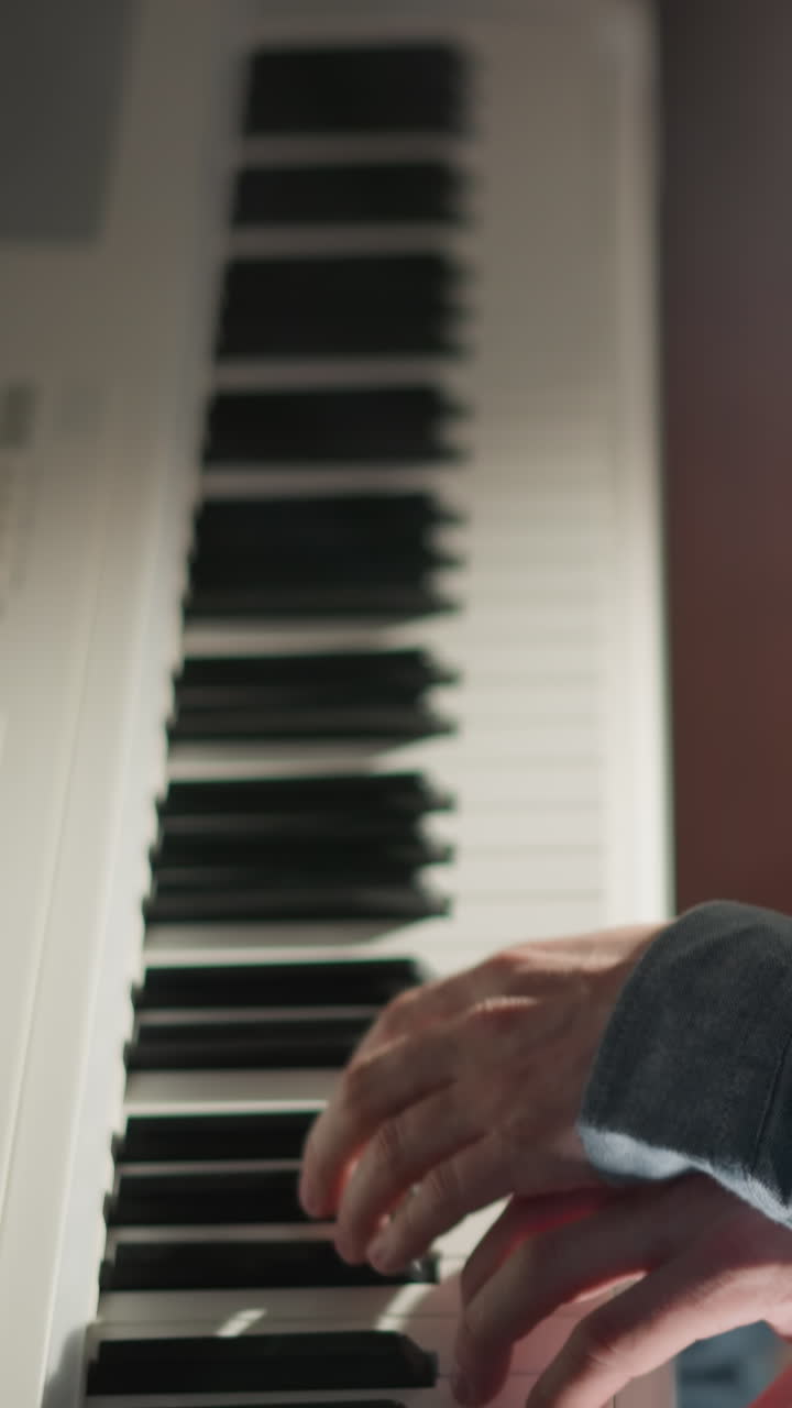 un hombre con una camisa azul tocando un piano blanco con enfoque y concentración. el fondo está borroso, llamando la atención al músico y su interacción con el instrumento