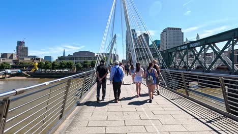 people walking on hungerford bridge in london