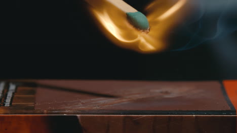 Green-tipped-matchstick-strikes-matchbox-and-ignites-a-flame-in-slow-motion