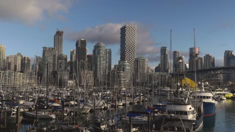 panorama of marina where small boats are anchored in the water in front of cityscape high rise buildings in the background blue sky clouds bridge metropolis