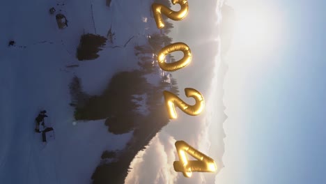 bright switzerland mountain aerial view with golden 2024 new year numbers