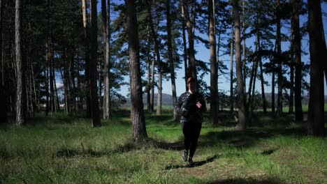 a woman runs in running clothes , surrounded by the beauty of the forest