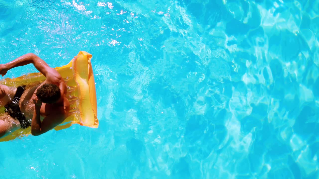 hombre en forma sentado en lilo en la piscina