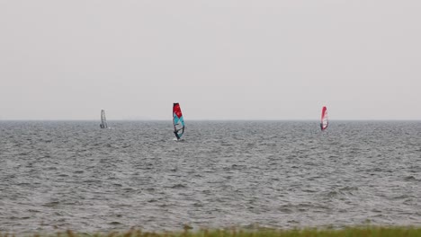 wind surfers sailing on an overcast windy day in the distance in pattaya, thailand