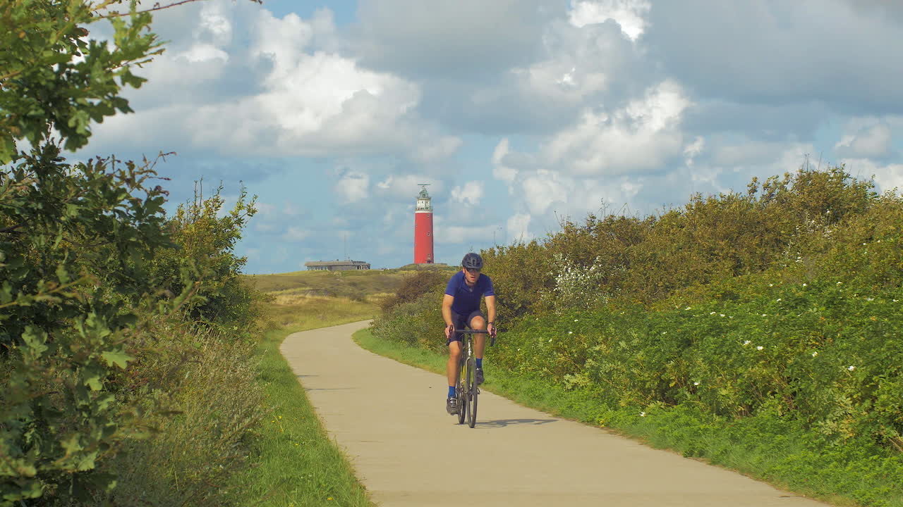 Cyclists on a path near a lighthouse