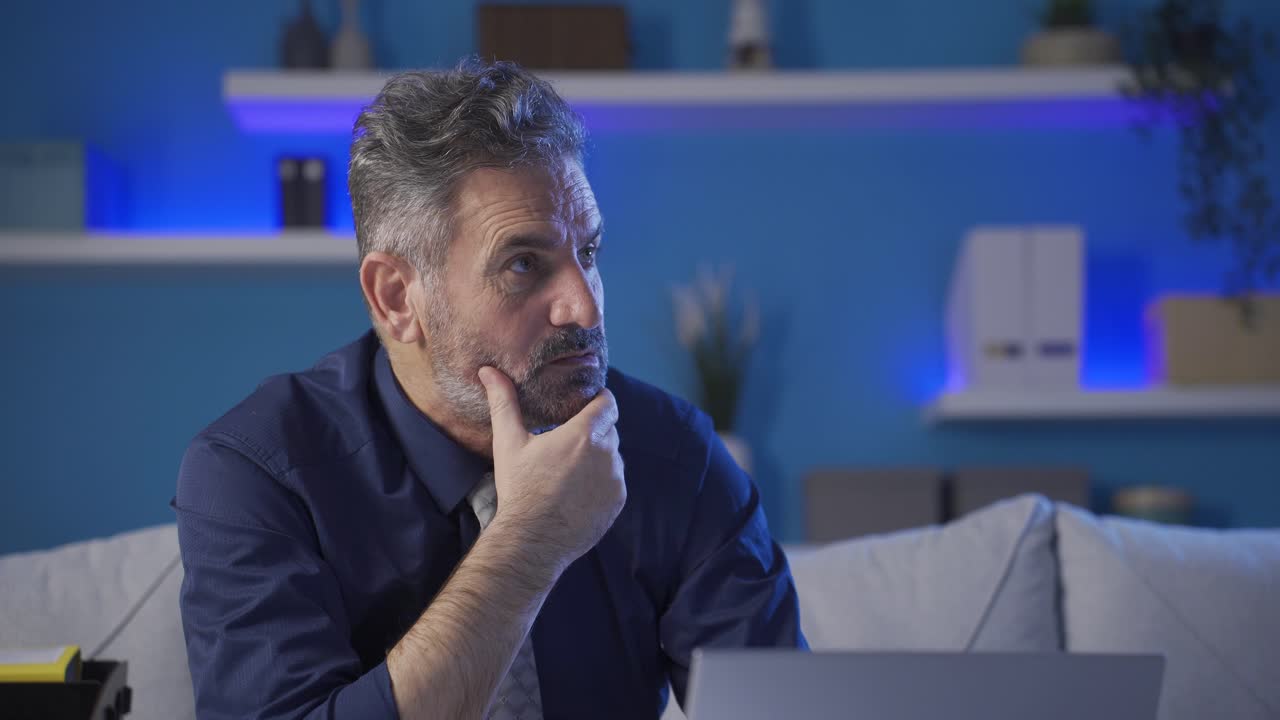 Thoughtful mature businessman working with laptop in home office.