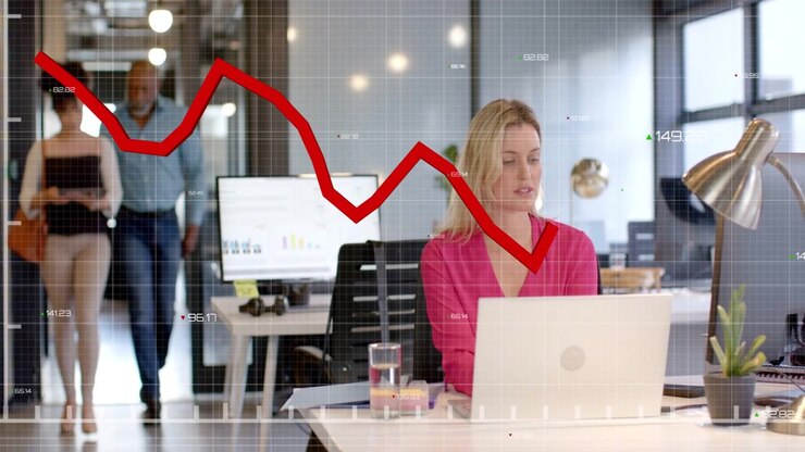 Seated woman working laptop in business, input driving red chart crossing torso as coworkers pass