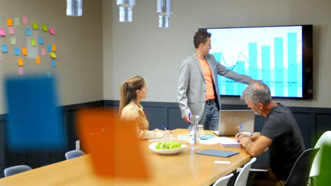 Businessman-discussing-with-colleagues-over-lcd-screen-in-conference-room-4k