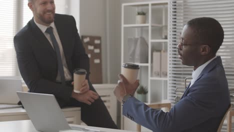 male financial accountants chatting during coffee break in office