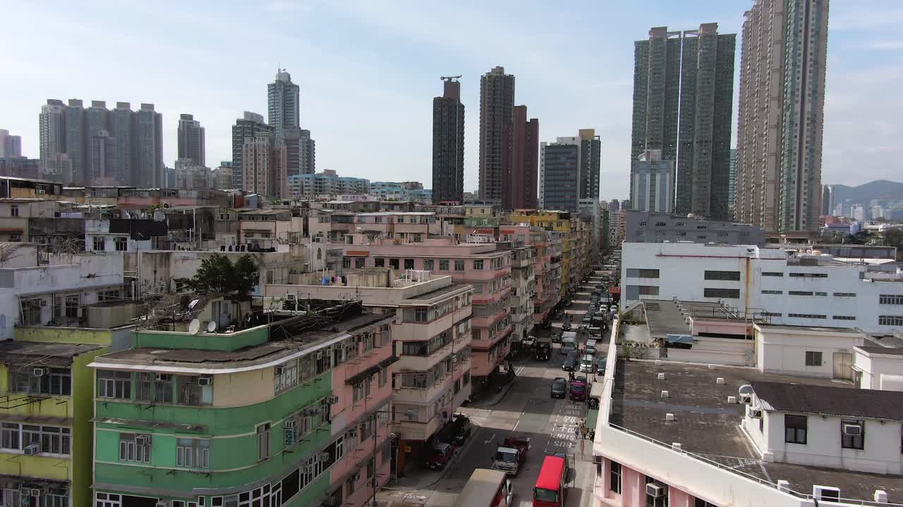 Aerial establish shot of Hong Kong Kowloon Walled City, a densely populated slum, with City skyscrapers in the background.