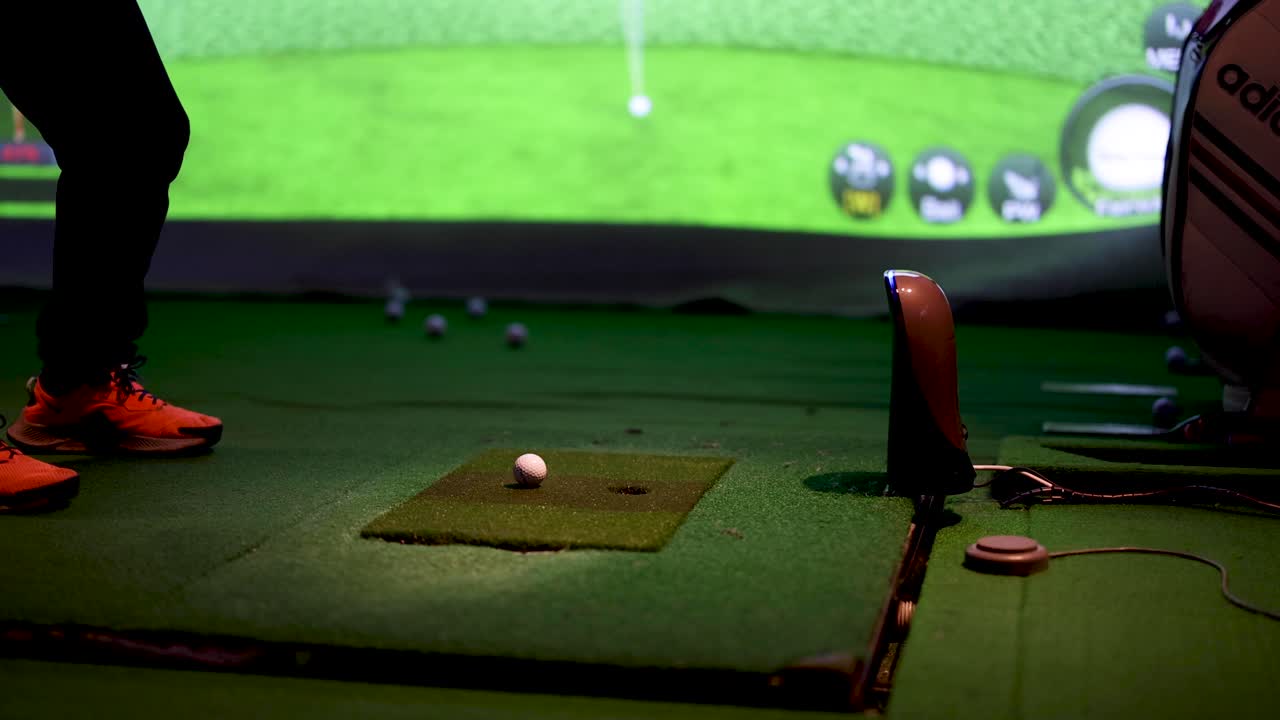 골퍼 가 실내 경기장에서 스 을 연습 하고 있다