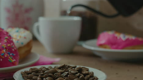 persona en el fondo vertiendo líquido en una taza con granos de café enfocados en el primer plano