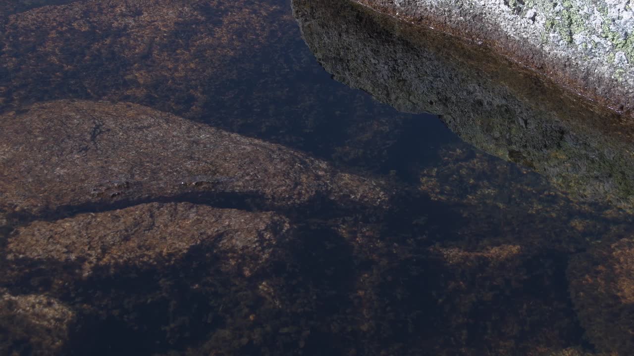 las rocas en el fondo del lago son visibles en el agua clara a través de la superficie ondulada