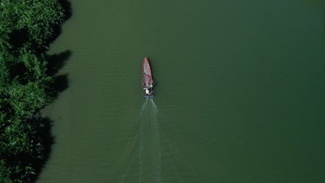 simple asian fishing boat traveling along clean emerald green mangrove coastline, aerial birds eye drone view, copy space