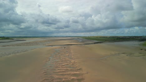 river estuary sandy bank with fly over of tributary on cloudy summer day