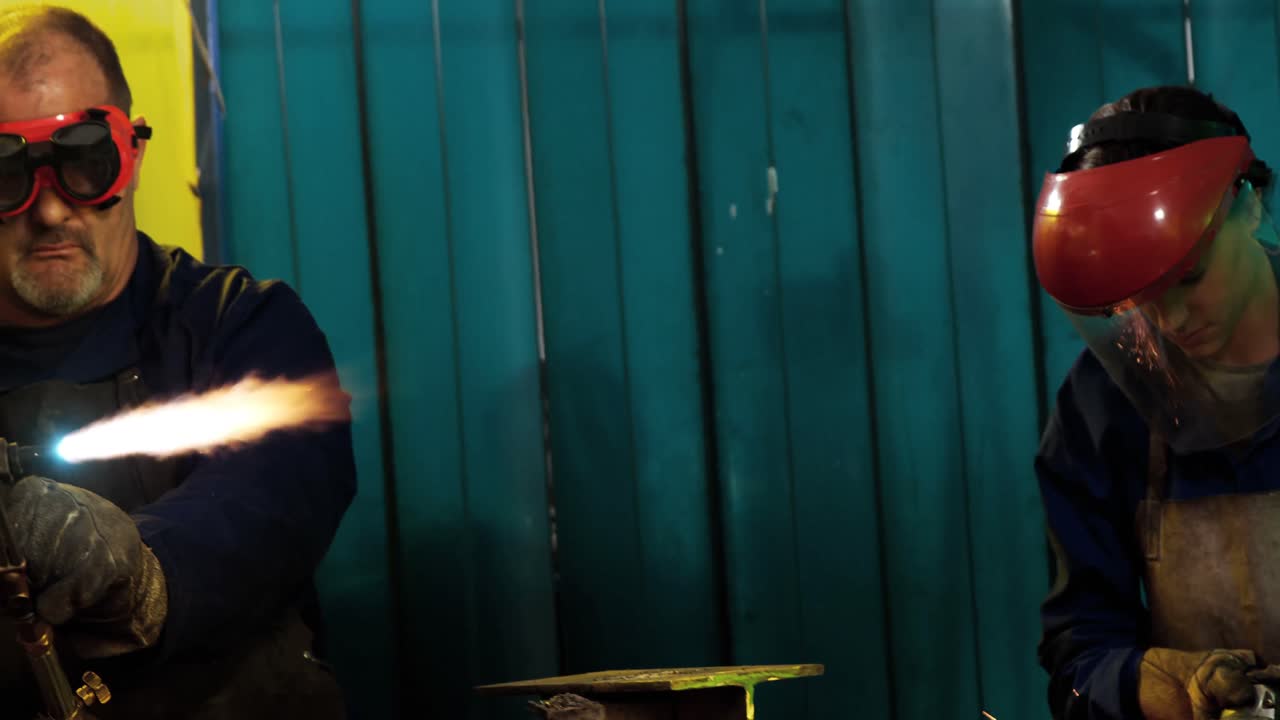 Male and female welders working in workshop