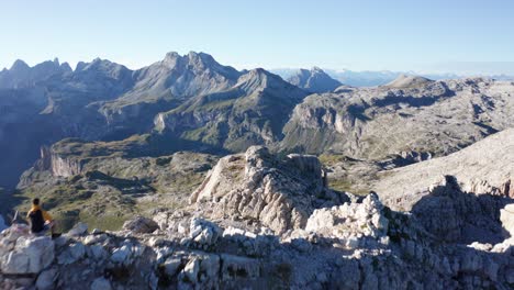 montañero sentado en el pico de la montaña en dolomitas, empuje aéreo