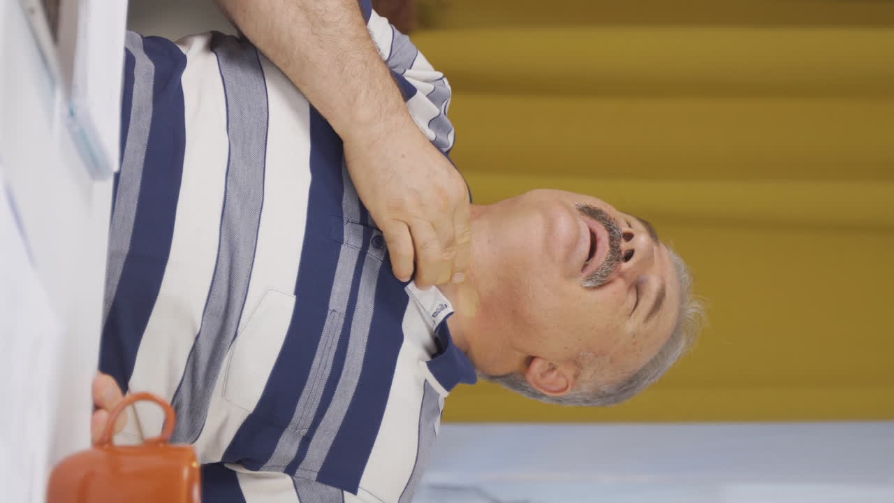 Vertical video of Home office worker old man suffering from sore throat.
