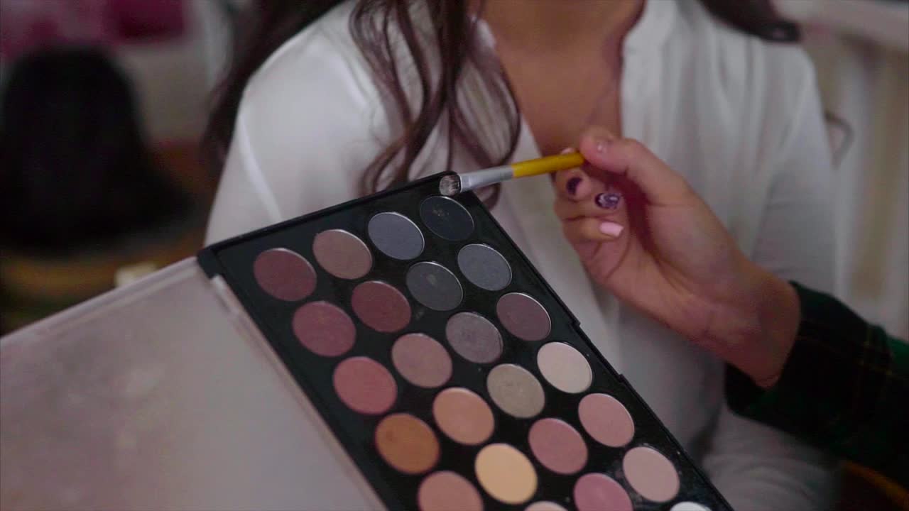 artista de maquillaje aplicando sombra de ojos