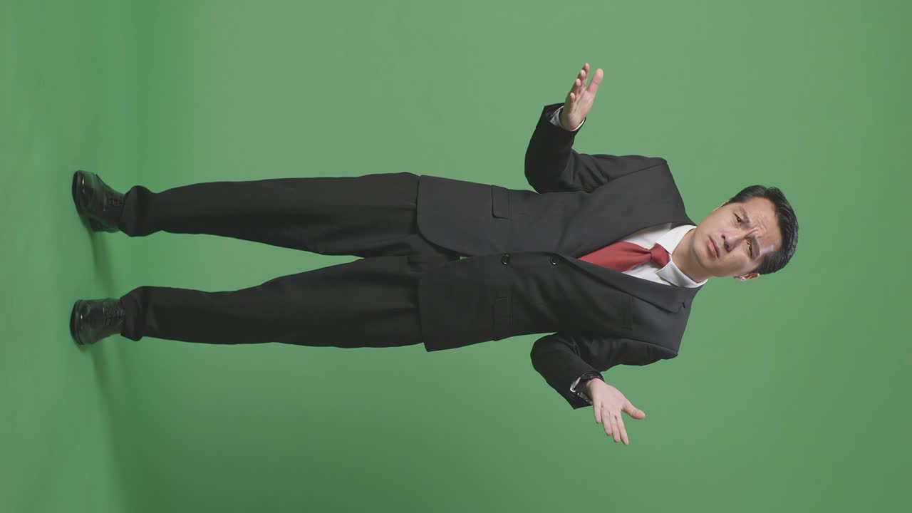 아시아 남성 사업가의 몸이 가득 차 있습니다. 혼란스러운 몸짓을 보여주고 녹색 화면 배경에서 무엇을 말하고 있습니다.