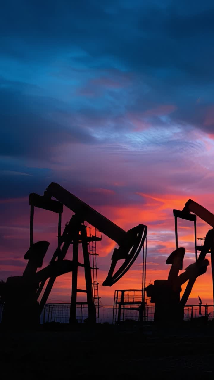 Tramonto Suggestivo su Pompe Petrolifere: Una Scena Accattivante che Mostra le Silhouette di Macchinari per Piattaforme Petrolifere Contro un Cielo dai Colori Vivaci al Crepuscolo.