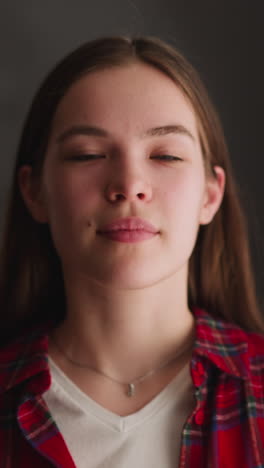 long haired cheerful woman in red shirt crosses arms and smiles standing in apartment zoom out slow motion. domestic life and casual clothes style