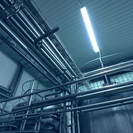 a number of steel tubes intertwisting with each other. premises with tubes lit by the daylight lamps. view from the below