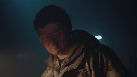 a bombmaker assembles a bomb in his workshop at night