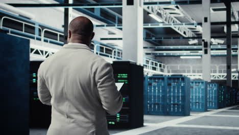 vertical video employee walking in server farm, analyzing equipment metrics on device screen