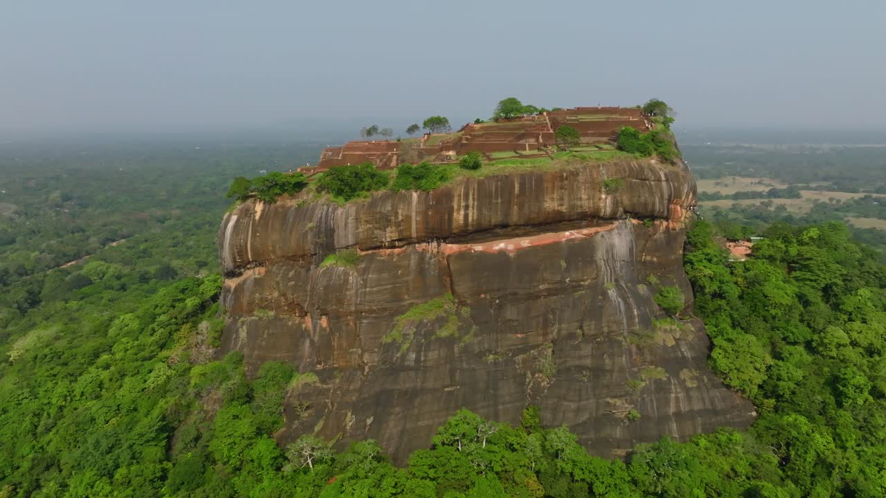 Dronebane over Sri Lanka over Sigiriya-toppens terrasser og gamle steinbygninger omgitt av et sterkt, grønt tak