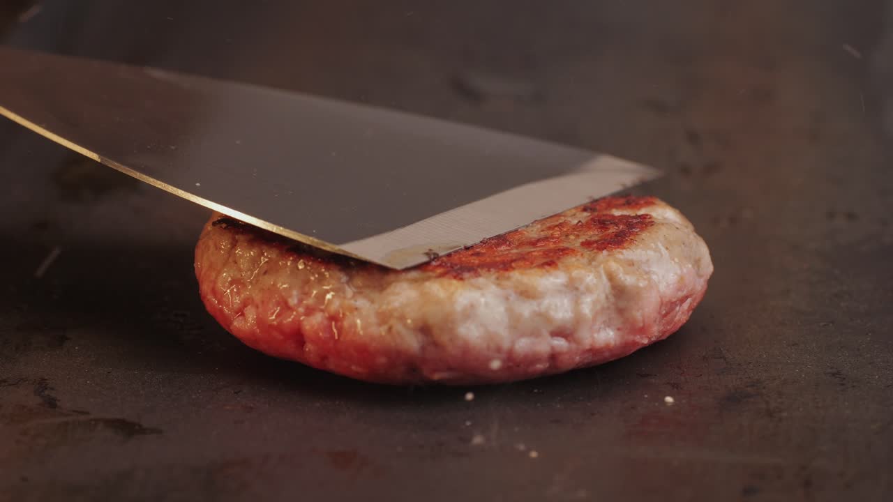 Cooking American fat smash burger on grill close-up. Beef or pork cutlet smashing by burger press. The chef in kitchen of the restaurant making cutlets for burgers - smash burger beefsteak. Fast and street food concept. High quality 4k footage