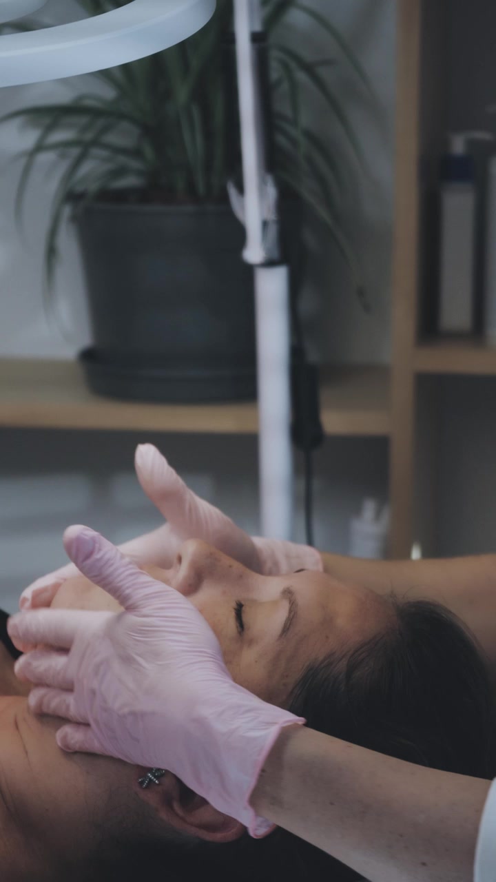 Esteticista realizando massagem facial em cliente em spa.