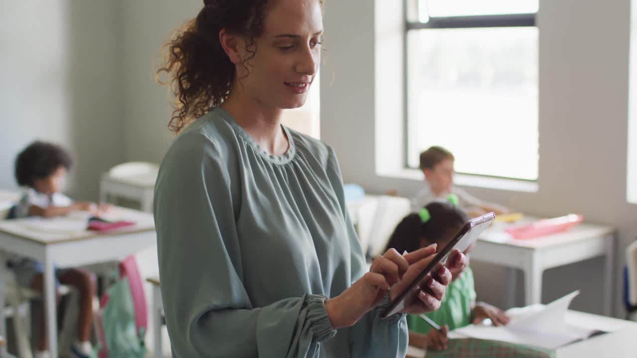 video de una feliz maestra caucásica usando una computadora portátil en la escuela durante las lecciones