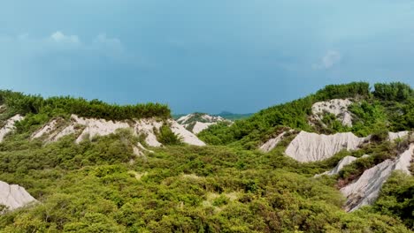 Aerial-flyover-green-vegetated-moonscape-during-cloudy-day-at-Tianliao-Moon-World,-田寮月世??