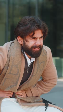 indian young business man feeling sudden strong abdominal stomach pain problem on city street