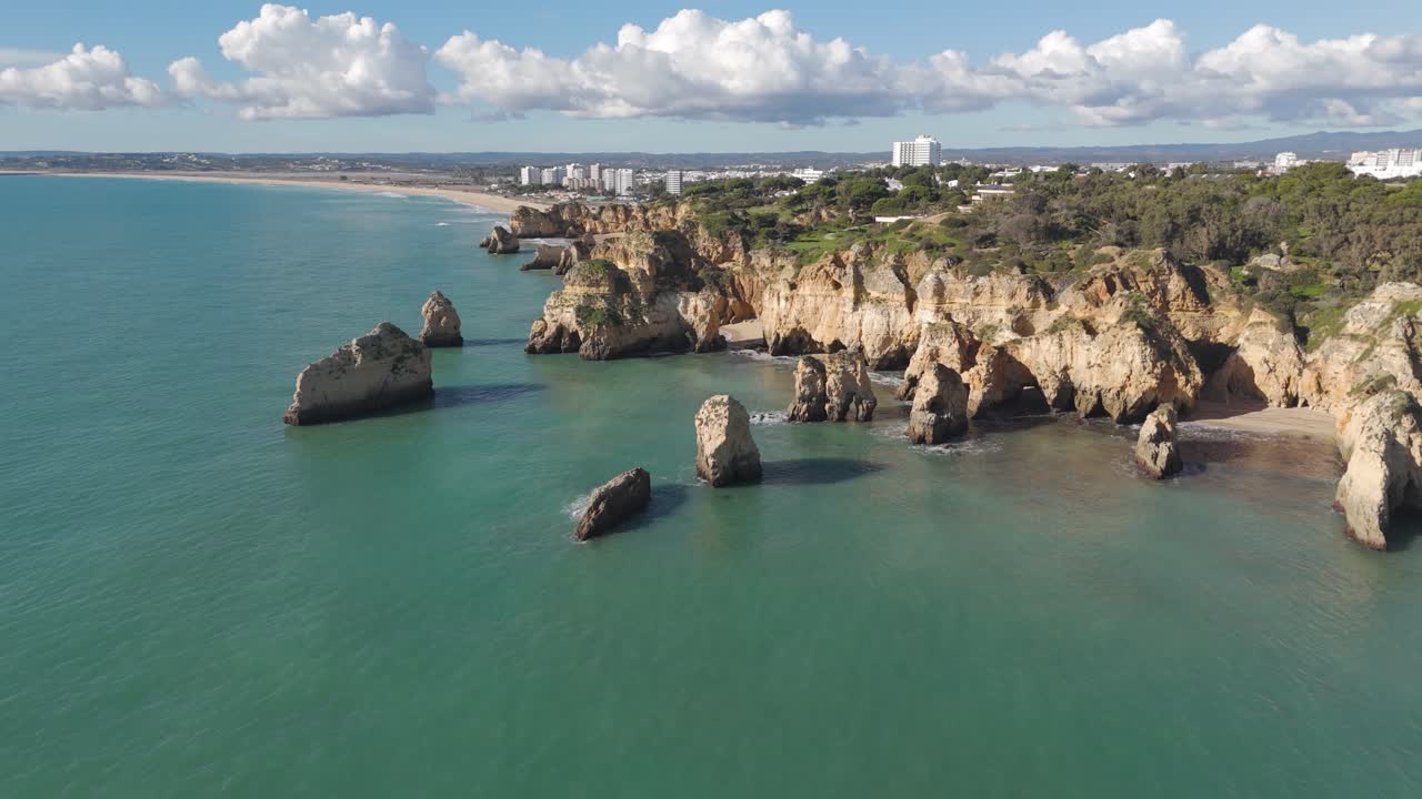 Flyfoto av Algarve-klippene i Portimão, Portugal, som viser gylne klipper og levende turkise farvann