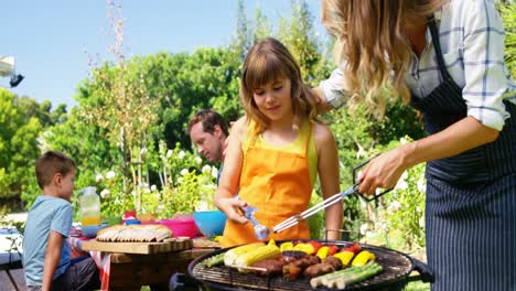 madre e hija asando carne y verduras en la barbacoa