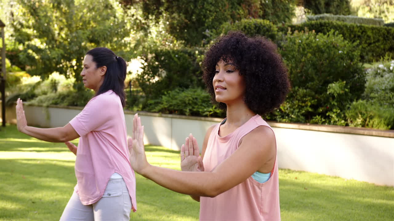 Practicing tai chi, mother and adult daughter enjoying outdoor exercise in park