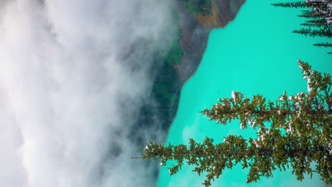 vertical 4k time lapse, clouds moving and disappearing above aqua blue water of lake louise, banff national park, alberta, canada