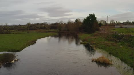 Aerial-view-flying-over-the-Gort-river-on-a-cloudy-evening